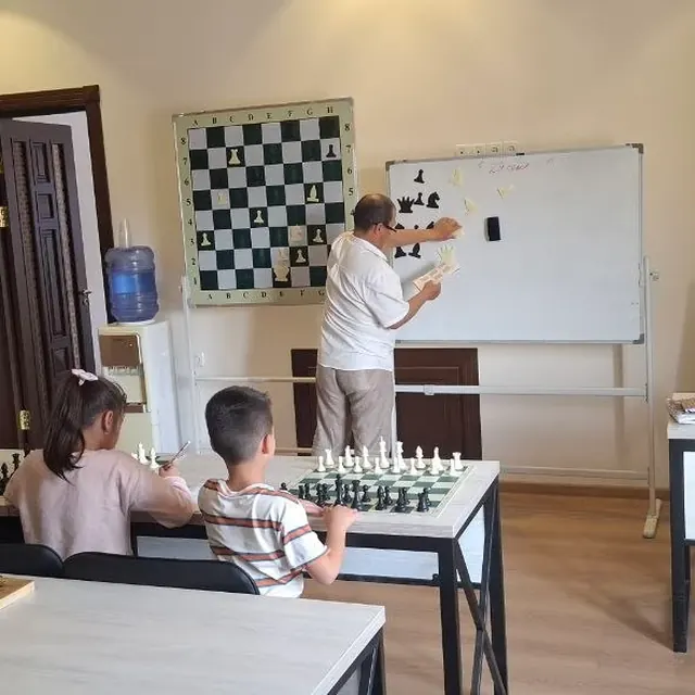Chess lesson: the teacher shows a move to students on a demonstration board