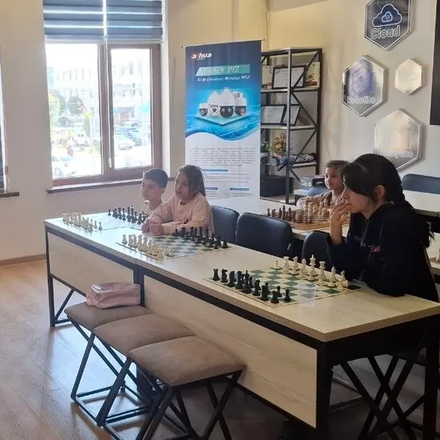Chess lesson: students at chess boards listening to the teacher
